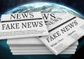 Fake news text on newspaper stack over planet earth world Royalty Free Stock Photo