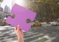 Hand holding jigsaw puzzle piece in city