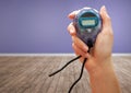 Hands holding stopwatch timer in purple room