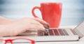 Hands with laptop and red coffee cup against blurry blue wood panel Royalty Free Stock Photo