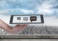 Holding tablet and Chat bubble icons over city Royalty Free Stock Photo