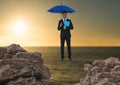 Digital composite image of businessman standing on rope holding diary with blue umbrella amidst rock Royalty Free Stock Photo