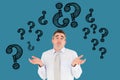 Digital composite image of confused businessman with question marks flying against blue background