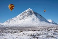 Digital composite image of hot air balloons flying over Beautiful iconic landscape Winter image of Stob Dearg Buachaille Etive Mor Royalty Free Stock Photo