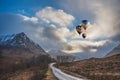 Digital composite image of hot air balloons flying over Stunning Winter sunset landscape of Etive Mor road leading between the Royalty Free Stock Photo