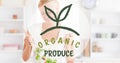 Digital composite image of organic produce symbol over smiling woman preparing salad at home