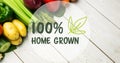 Digital composite image of 100 percent home grown symbol over fresh vegetables on wooden table