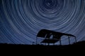 Digital composite image of star trails around Polaris with derelict barn silhouette