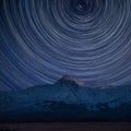 Digital composite image of star trails around Polaris with Eic landscape image of Snowdonia snowcapped mountains