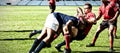 Digital composite image of team of rugby players tackling each other to win the ball in stadium Royalty Free Stock Photo