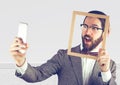 Millennial man holding picture frame and phone Royalty Free Stock Photo