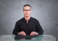 Nerd man at desk against grey wall with grunge overlay Royalty Free Stock Photo
