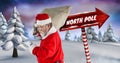 North Pole text and Santa holding sack with Wooden signpost in Christmas Winter landscape Royalty Free Stock Photo