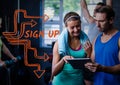 Orange sign up text next to man and woman and tablet in gym Royalty Free Stock Photo