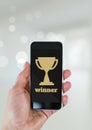 Person holding a phone with a trophy icon Royalty Free Stock Photo