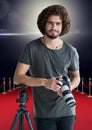 photographer rest on tripod, with the camera on hands in the red carpet. Flares behind