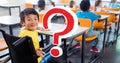 Digital composite of red question mark over smiling disabled schoolboy sitting at desk in classroom Royalty Free Stock Photo