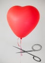 Scissors cutting heart balloon string