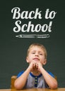 Student boy at table against green blackboard with back to school text Royalty Free Stock Photo