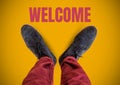 Welcome text and Grey shoes on feet with yellow background