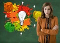 Woman standing ext to light bulb with colorful crumpled paper balls in front of blackboard Royalty Free Stock Photo