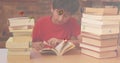 Digital composition of multiple alphabets floating against boy reading a book in library Royalty Free Stock Photo