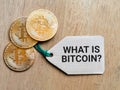 Phrase WHAT IS BITCOIN written on label tag with bitcoin.
