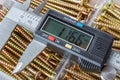 Digital electronic caliper on a background of opened storage box with yellow long screws closeup Royalty Free Stock Photo