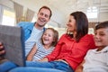 Digital entertainment for the whole family. smiling parents sitting with their young son and daughter on their living Royalty Free Stock Photo