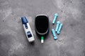 Digital glucometer and lancet pen on gray background, close-up. Diabetes concept. Blood glucose meter