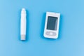 Digital glucometer and lancet pen on pastel blue background. Top view. Diabetes concept