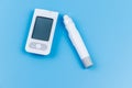 Digital glucometer and lancet pen on pastel blue background. Top view. Diabetes concept