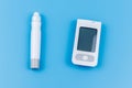 Digital glucometer and lancet pen on pastel blue background. Top view. Diabetes concept