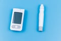 Digital glucometer and lancet pen on pastel blue background. Top view. Diabetes concept