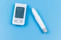 Digital glucometer and lancet pen on pastel blue background. Top view. Diabetes concept