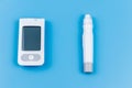 Digital glucometer and lancet pen on pastel blue background. Top view. Diabetes concept