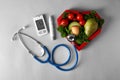 Digital glucometer with lancet pen, stethoscope and healthy food on grey background. Diabetes diet