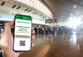 The digital green pass of the european union with the QR code on the screen of a mobile held by a hand with a blurred airport in