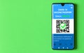 Digital health passport of COVID-19 vaccination in mobile phone on green background