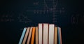 Digital image of a pile of books while mathematical equations and graphs move in the screen against Royalty Free Stock Photo