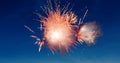 Digital image of red fireworks exploding in the blue sky