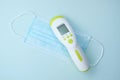 medical infrared non contact thermometer gun for measuring temperature, face mask on blue background Royalty Free Stock Photo