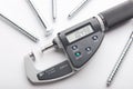 Digital micrometer with adjustable pressure measurement with steel screws on white background.