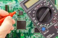 Digital multimeter and engineer`s hand with probe on the circuit board background Royalty Free Stock Photo