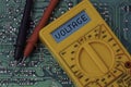 Digital multimeter multitester on a circuit board with the word voltage Royalty Free Stock Photo
