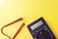 Digital multimeter with probes and backlit display on a yellow background. A multimeter or a multitester is an electronic Royalty Free Stock Photo