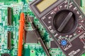 Digital multimeter and probes on a green circuit board closeup Royalty Free Stock Photo