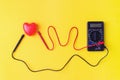 Digital multimeter with probes and red heart on a yellow background. Healthy Concept. Vital energy concept Royalty Free Stock Photo