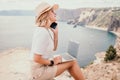 Digital nomad, Business woman working on laptop by the sea. Pretty lady typing on computer by the sea at sunset, makes a