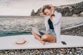 Digital nomad, Business woman working on laptop by the sea. Pretty lady typing on computer by the sea at sunset, makes a